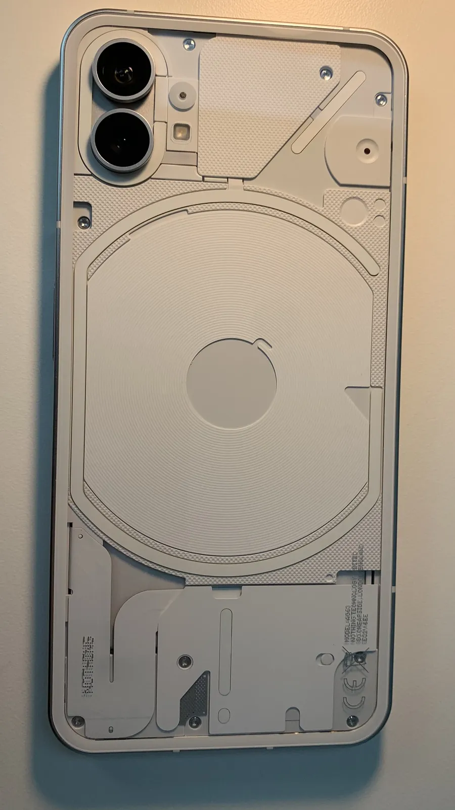 The transparent white back of a Nothing Phone (1), its Glyph light strips and wireless charging coil visible